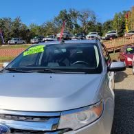 Silver car with a neon green windshield sale sign parked outdoors on a sunny day