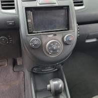 Car dashboard center console with a touchscreen, climate controls, and gear shift.