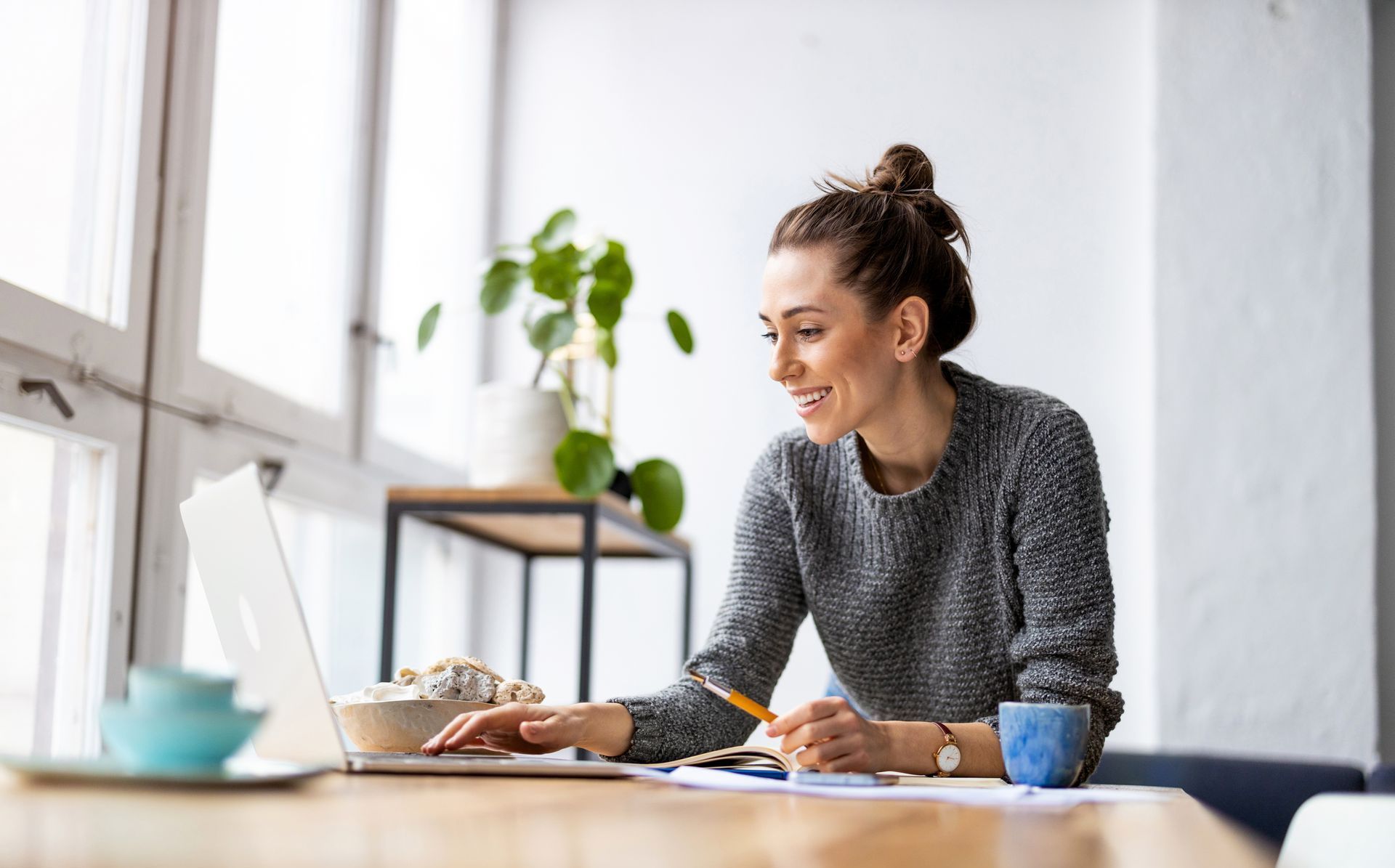 A woman is sitting at a table using a laptop computer.