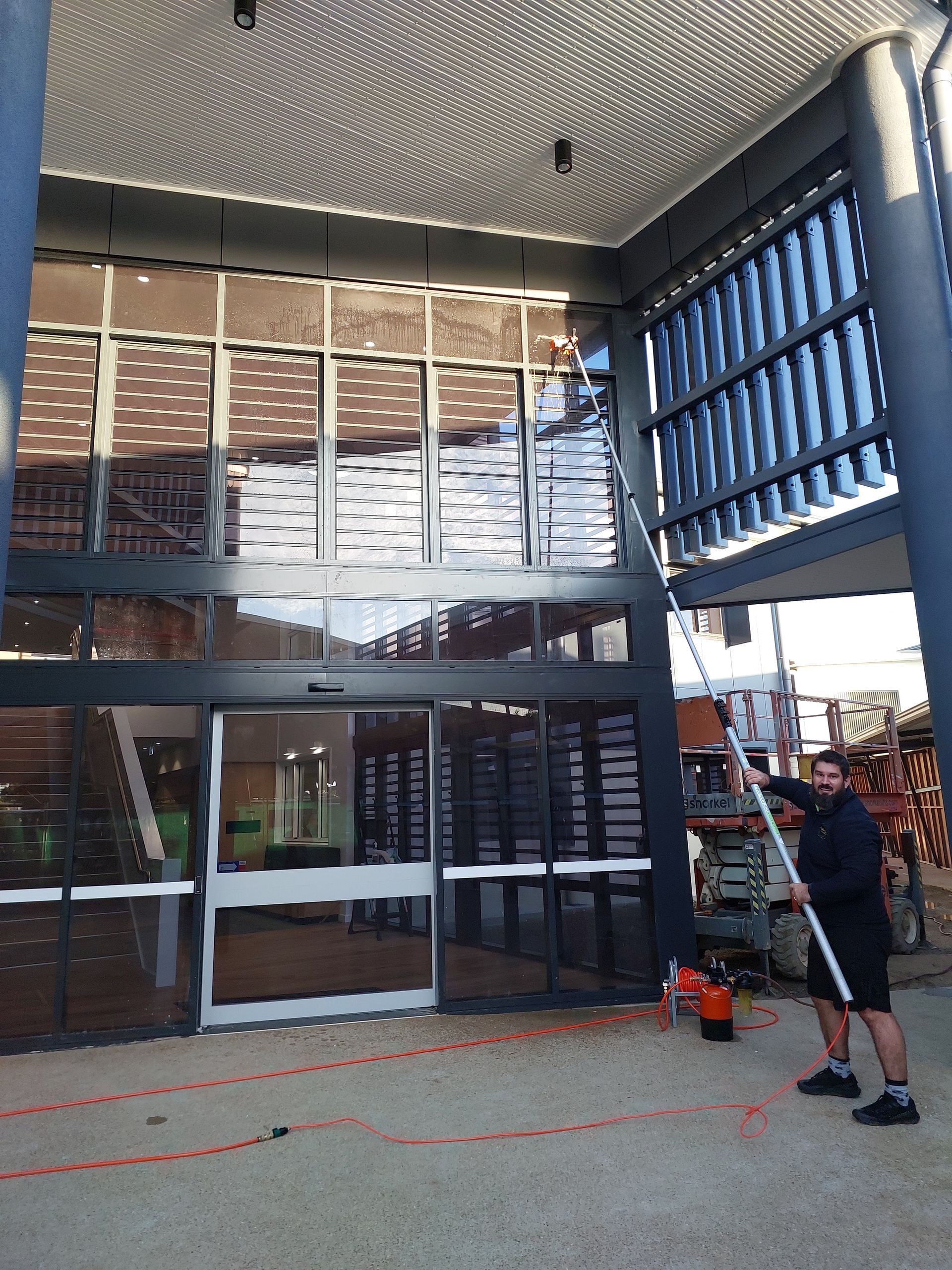 Modern Building Facade With a Large Perforated Canopy and a Person Standing — Pristine Cleaning Bundaberg In Kalkie, QLD
