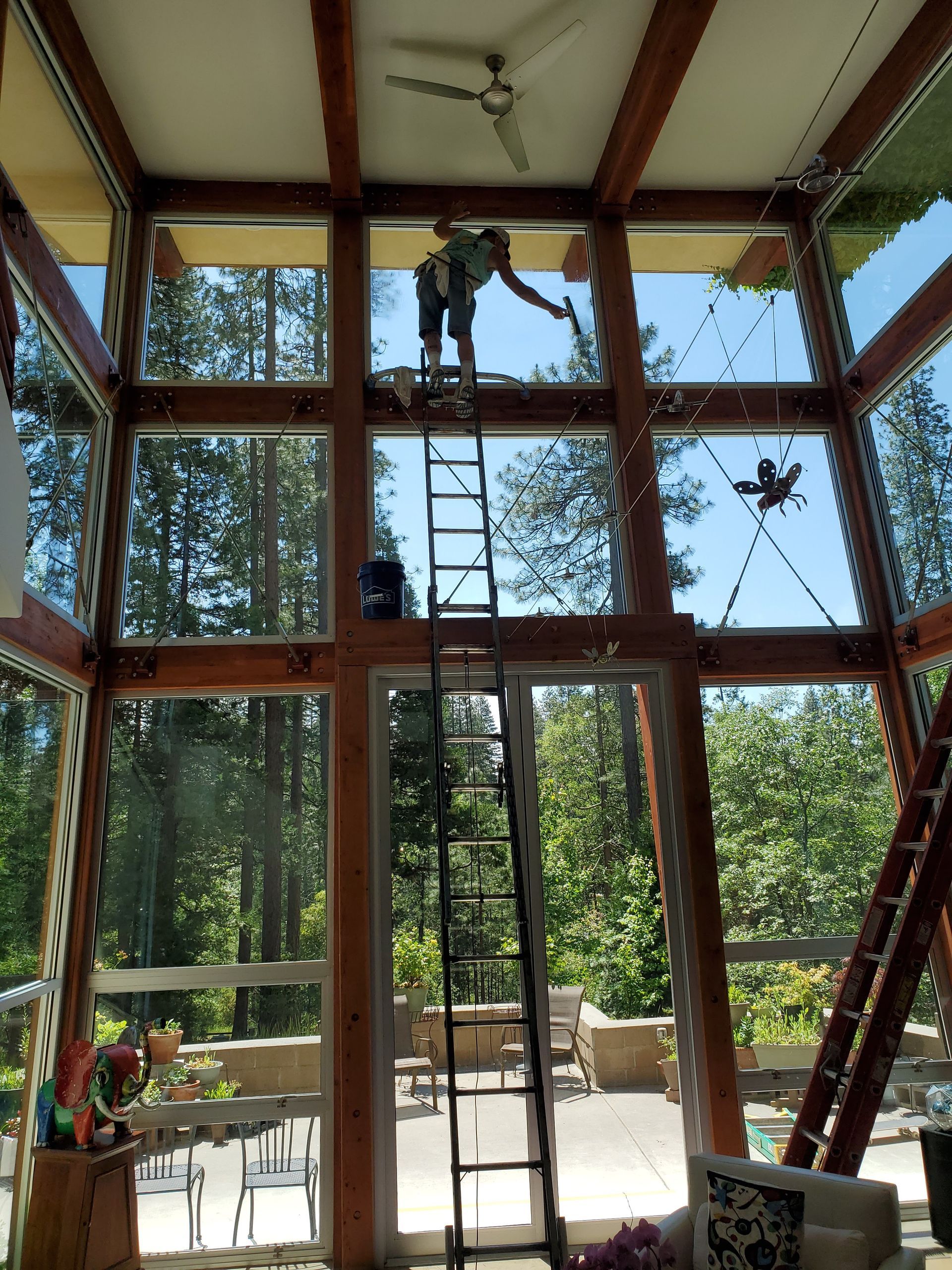 A man on a ladder cleaning a window in a house