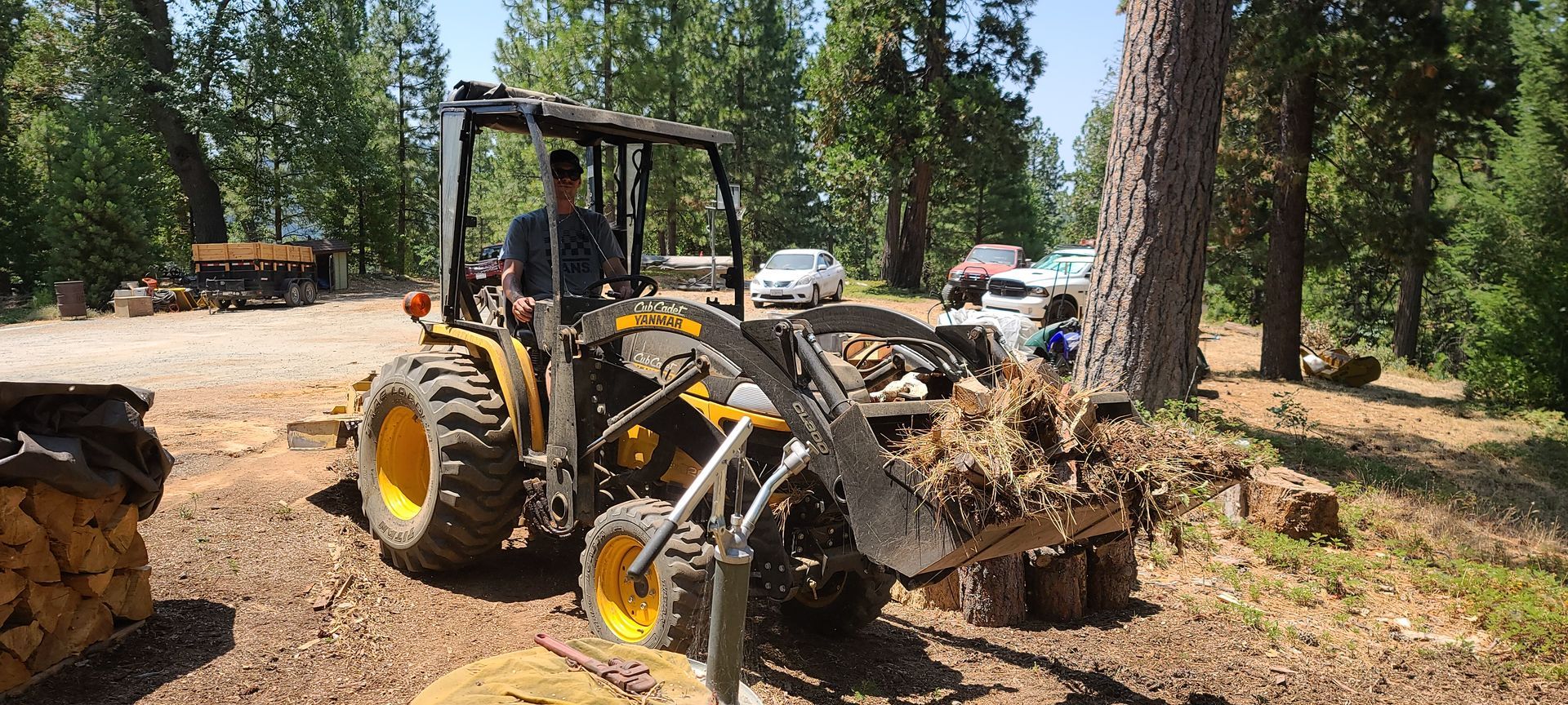 A man is driving a tractor with a fork attached to it.