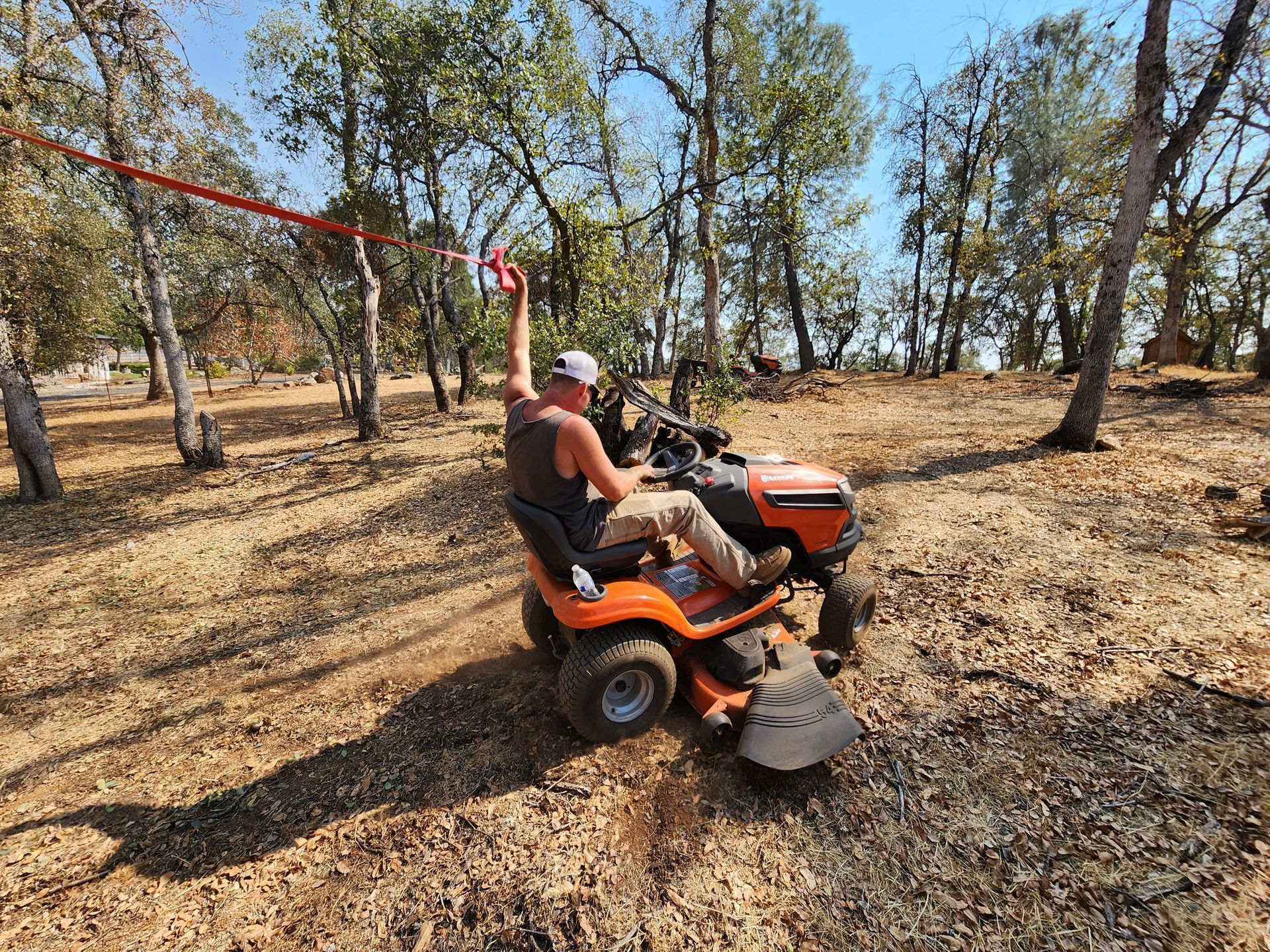 A man is riding a lawn mower in the woods.
