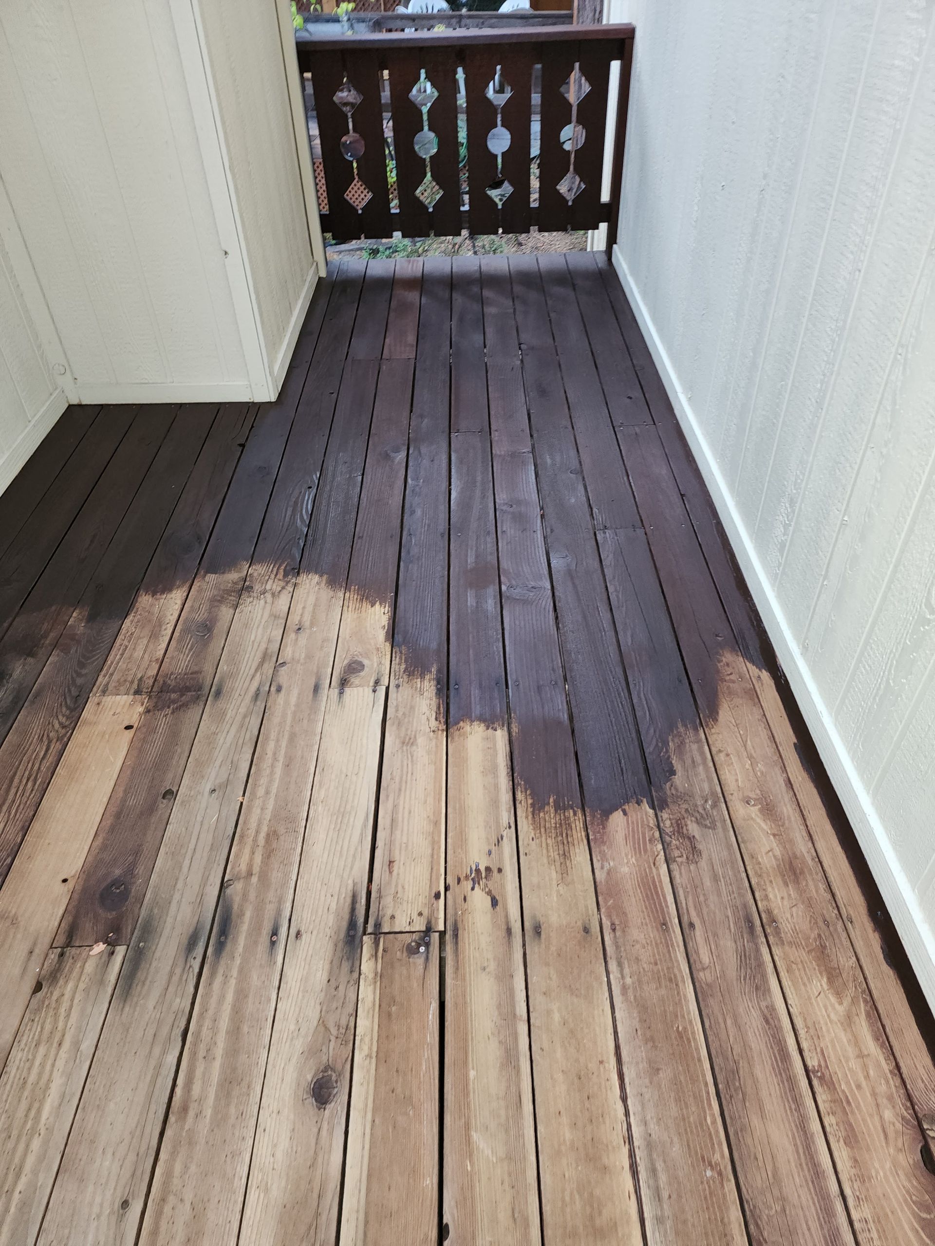 A wooden deck is being painted in a room with a balcony.