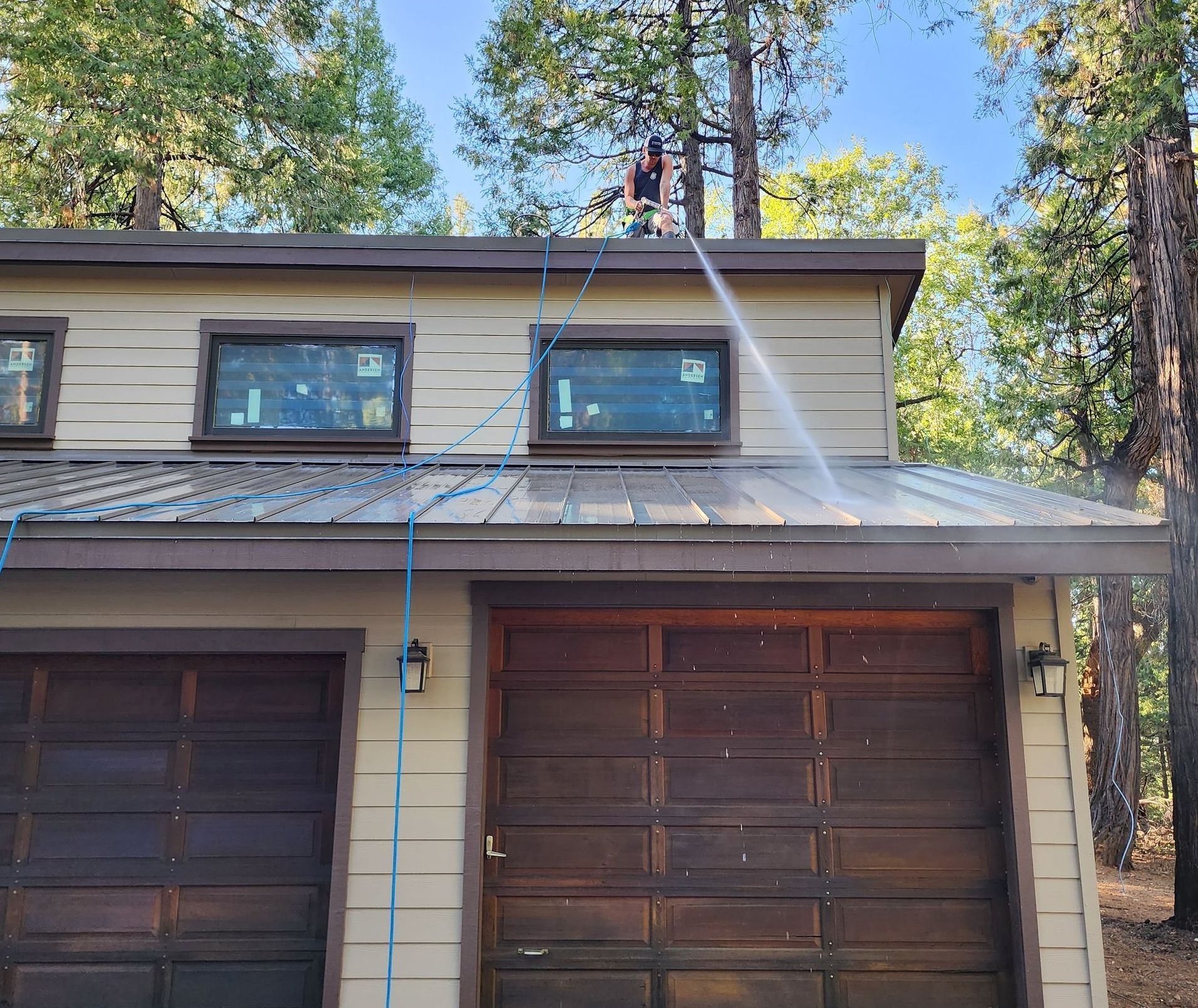 A man is cleaning the roof of a house with a pressure washer.