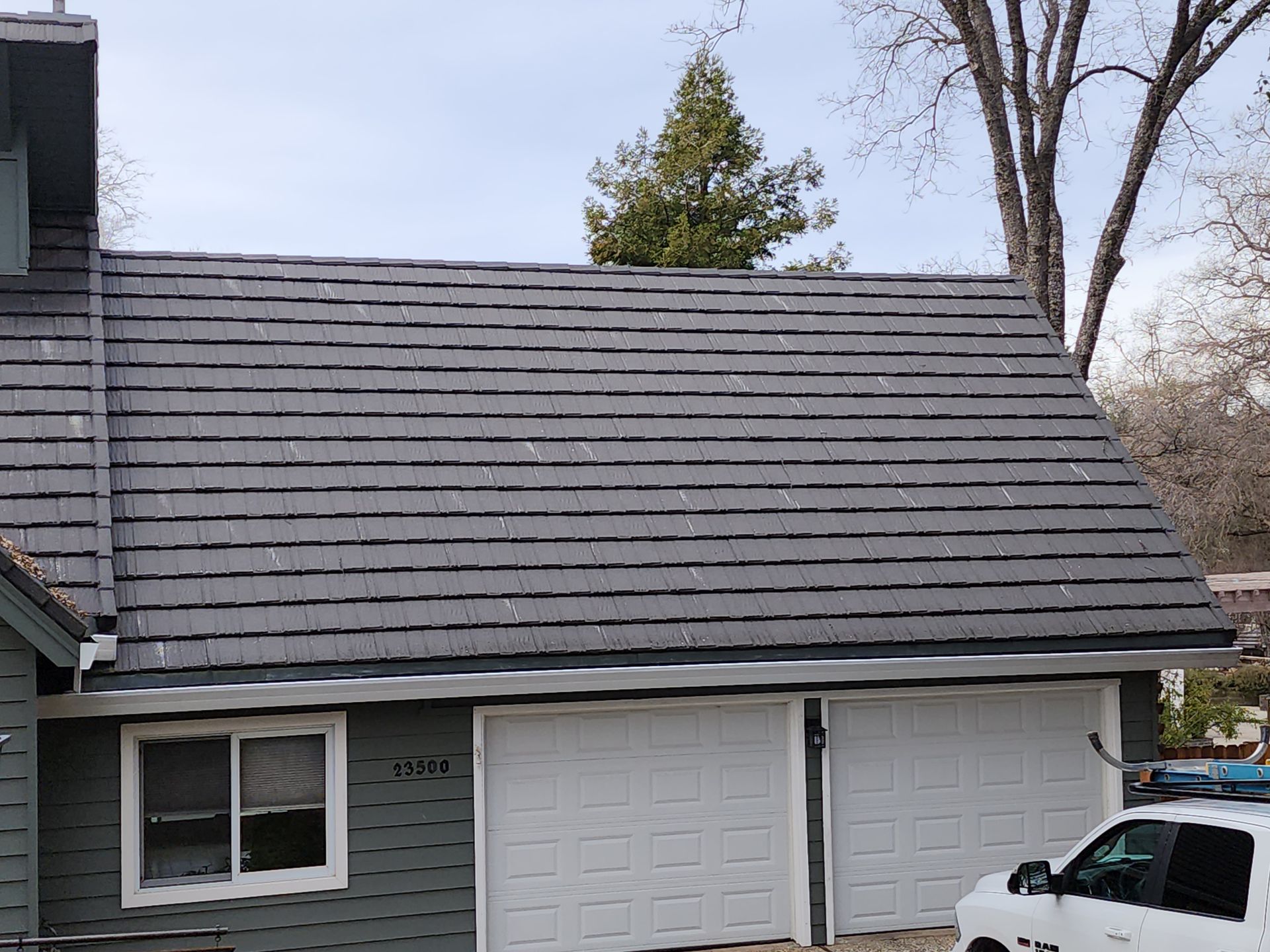 A car is parked in front of a house with a slate roof.