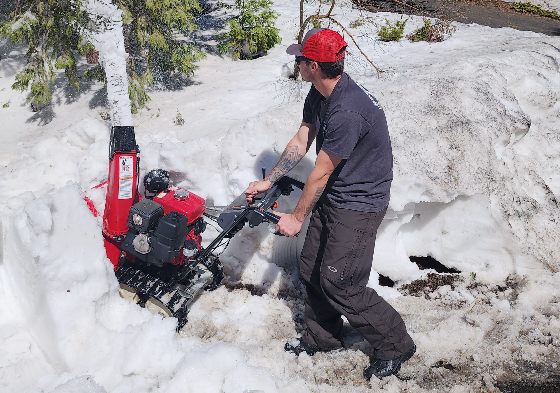 A man is pushing a snow blower through the snow
