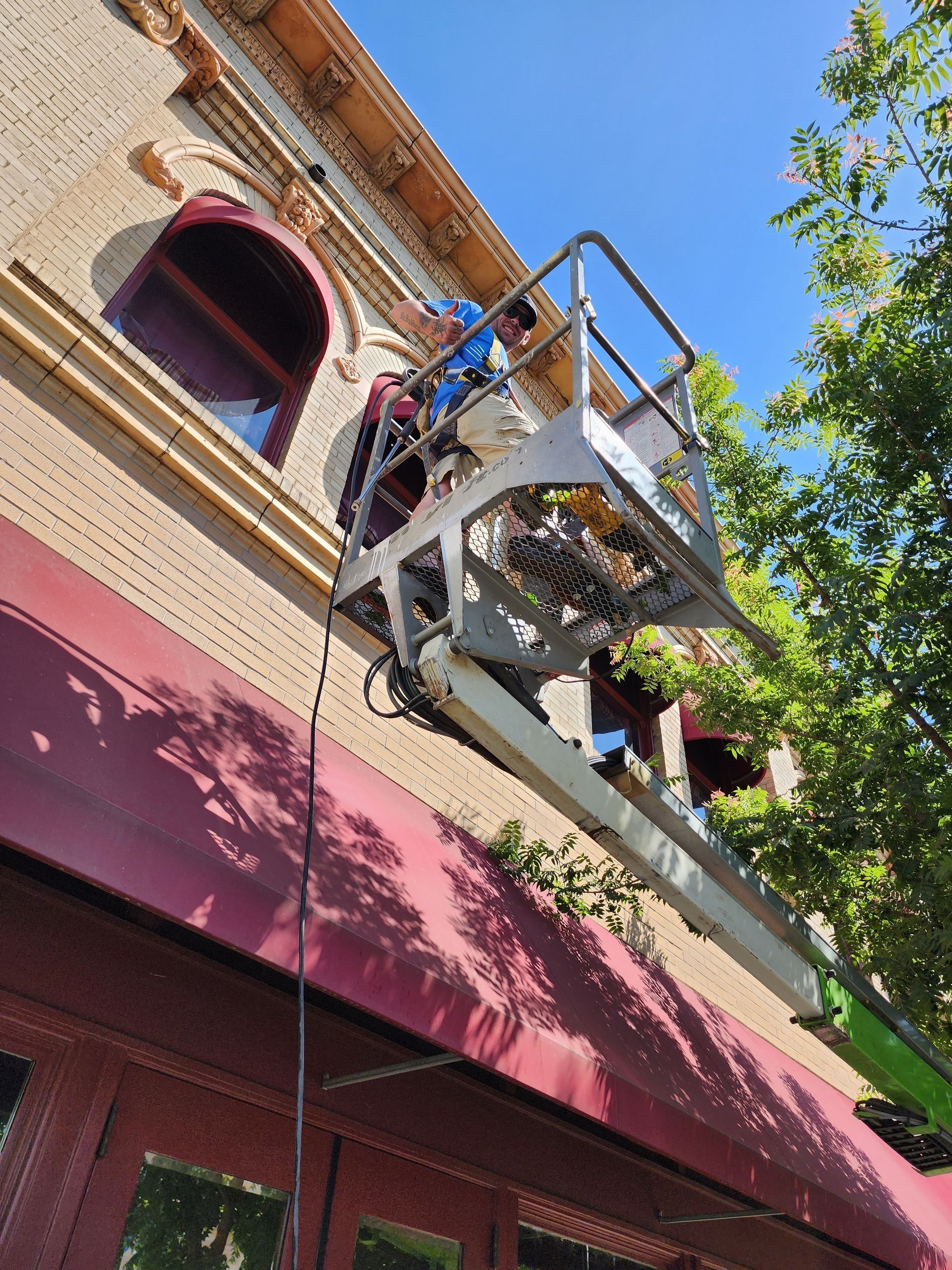 A man is standing on a lift on the side of a building.