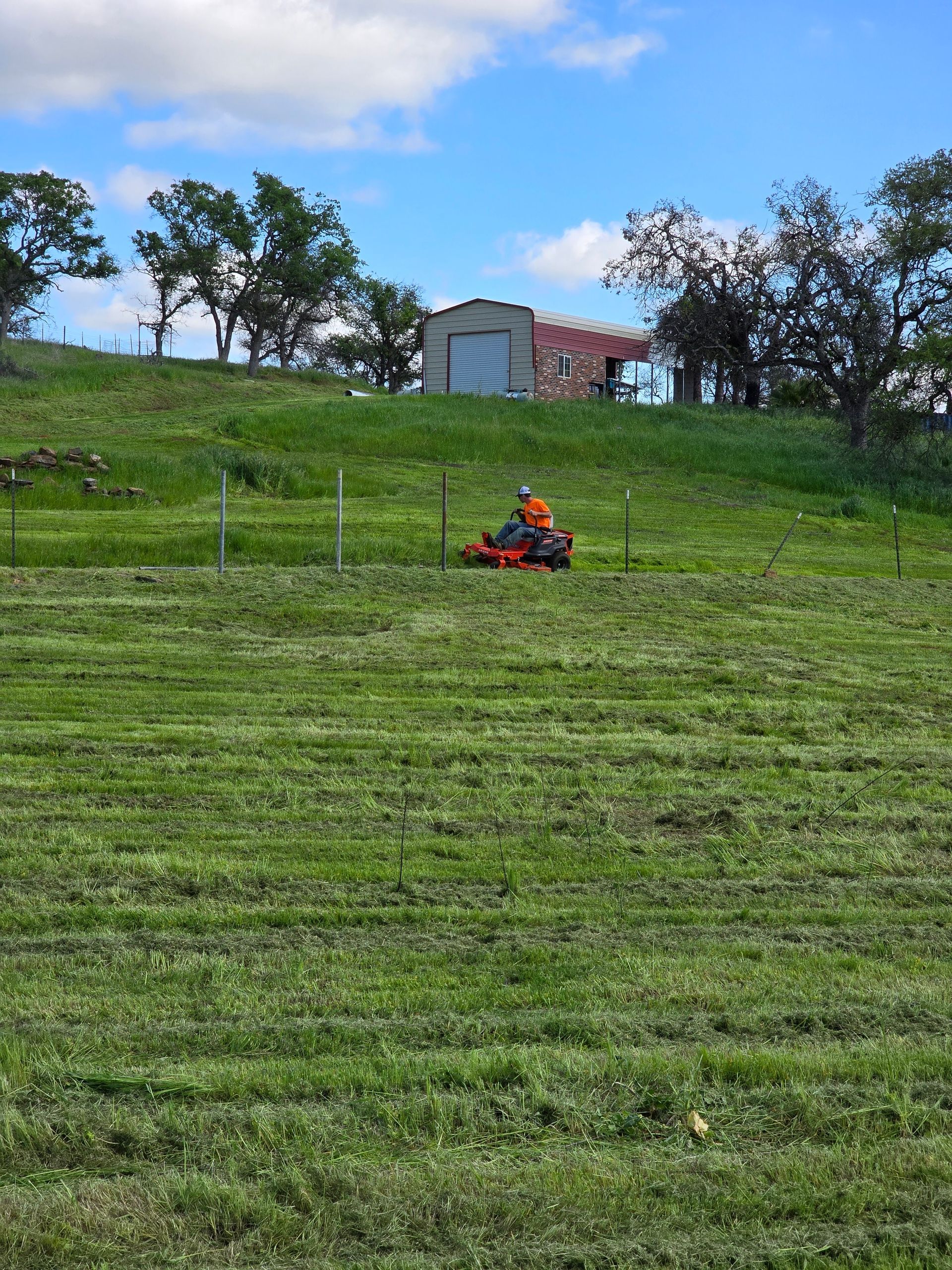A person is riding a lawn mower in a grassy field.