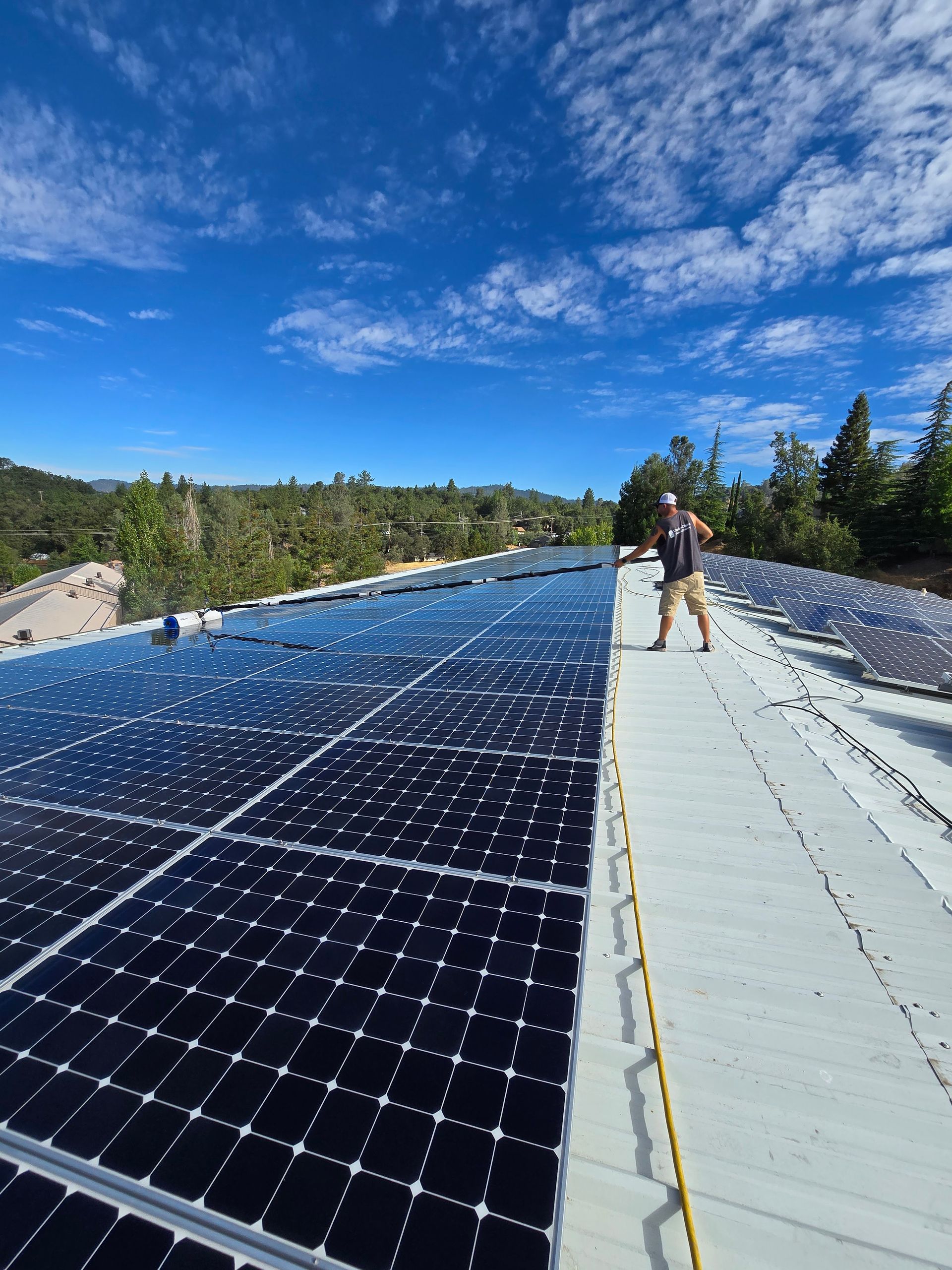 A man standing on top of a roof with solar panels