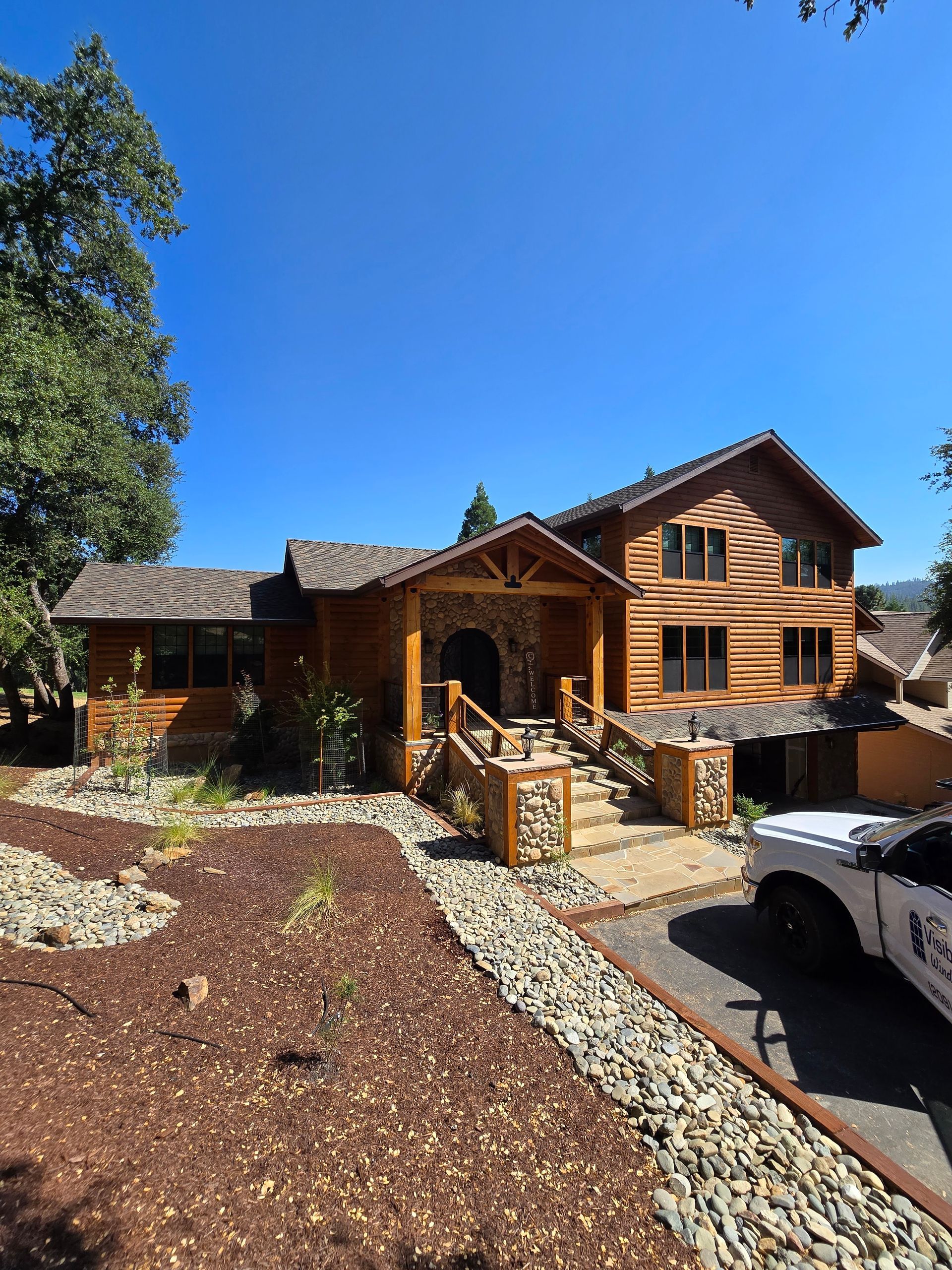 A large wooden house with a white truck parked in front of it.