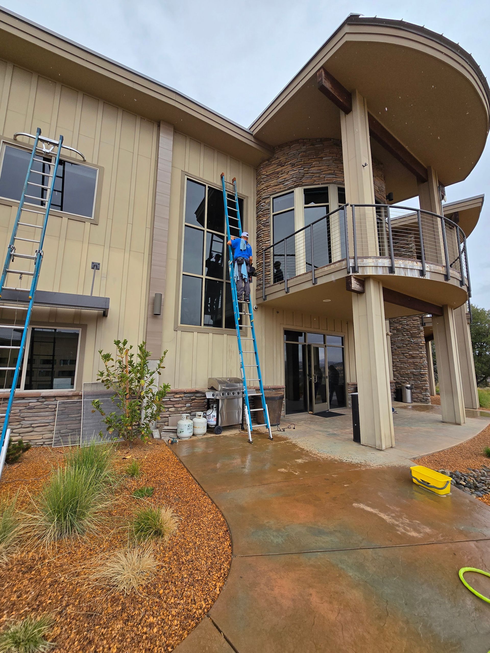 A man is standing on a ladder in front of a large house.