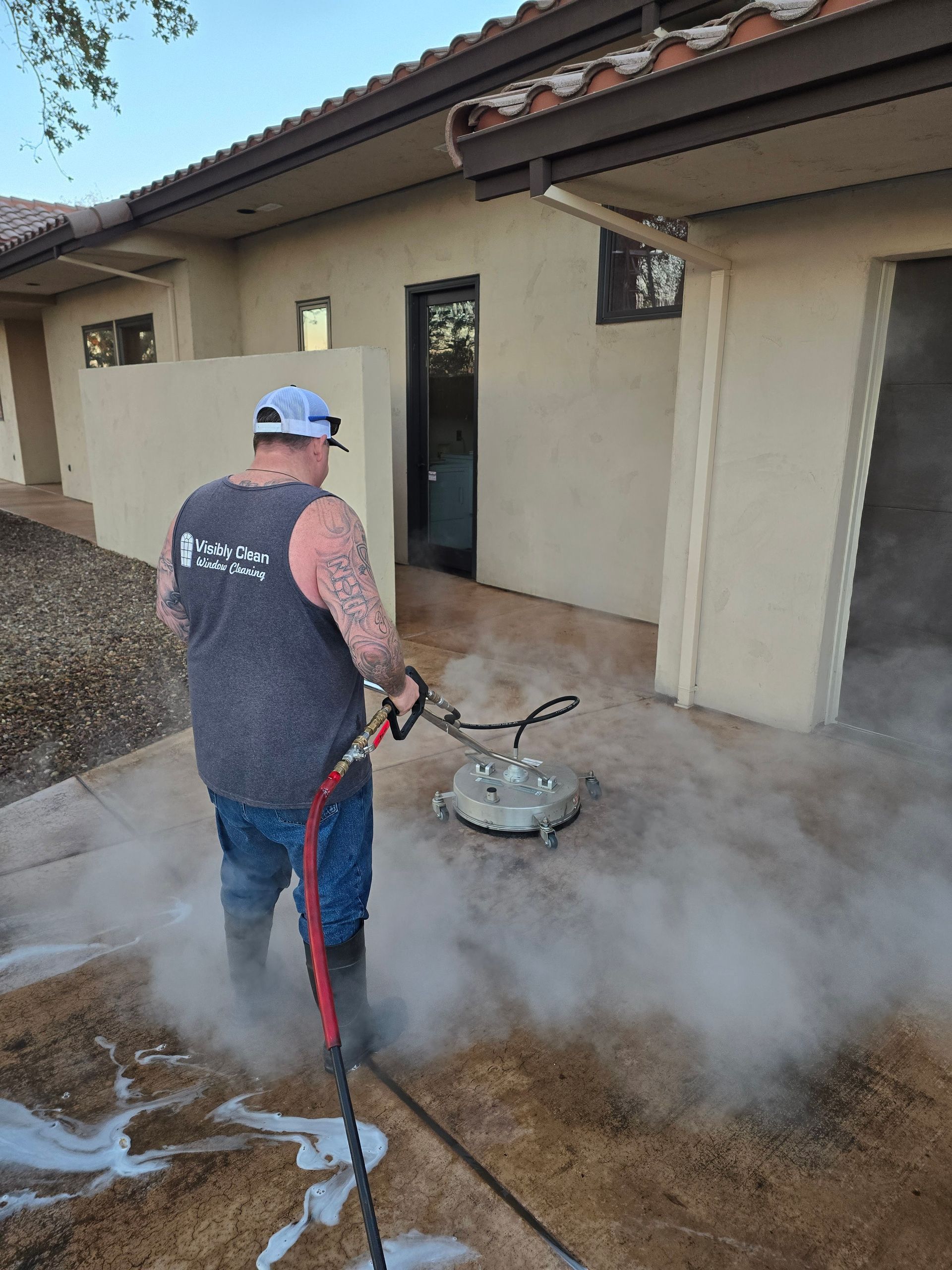 A man is cleaning a concrete patio with a pressure washer.