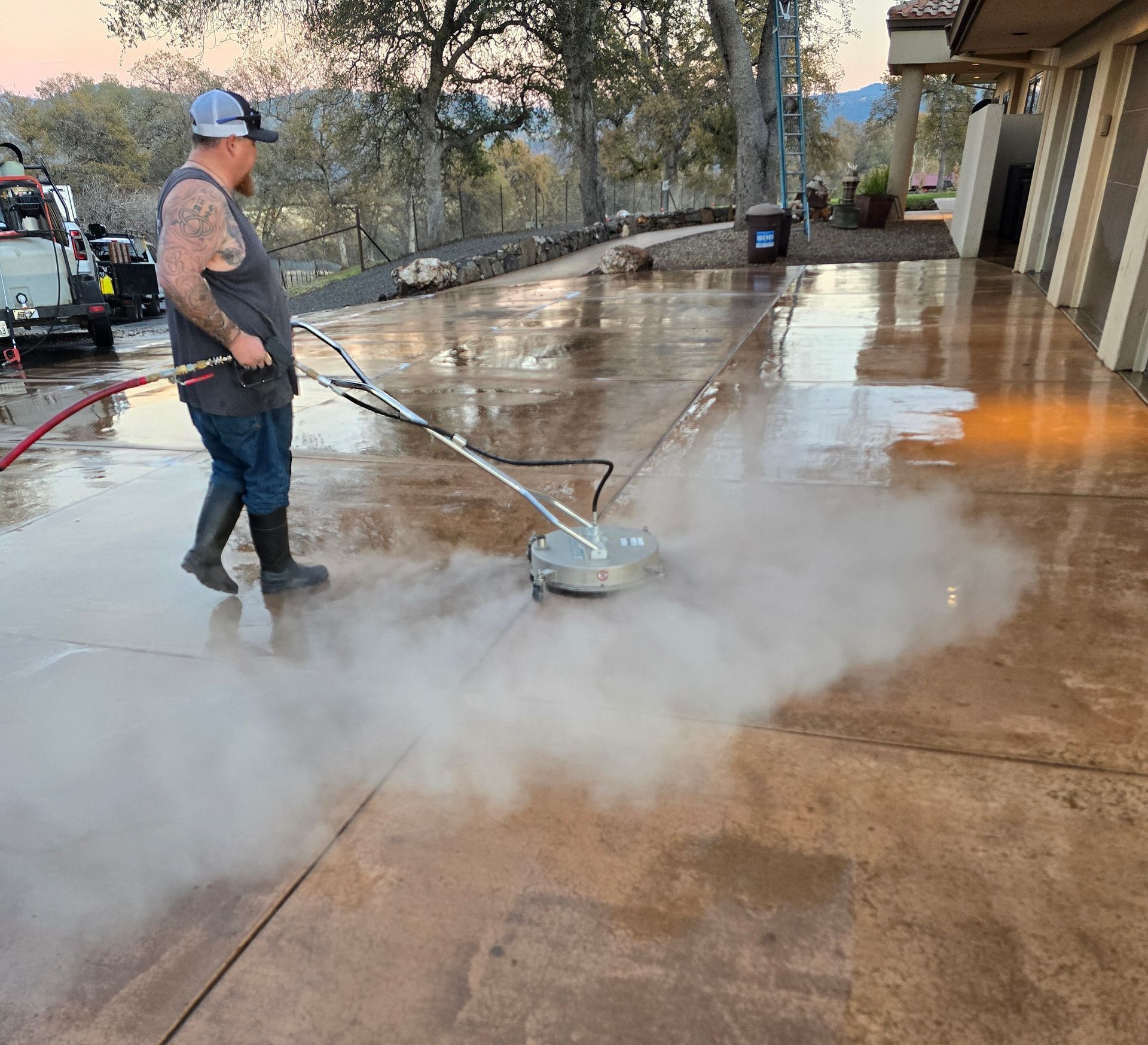 A man is cleaning a concrete driveway with a machine.