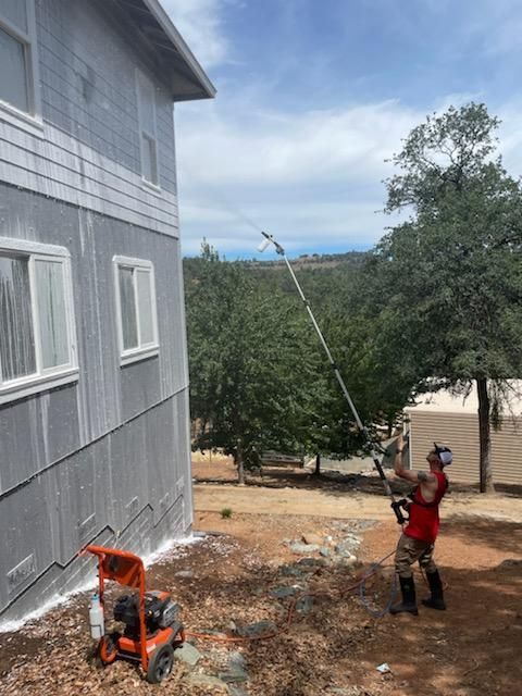 A man is spraying paint on the side of a building.