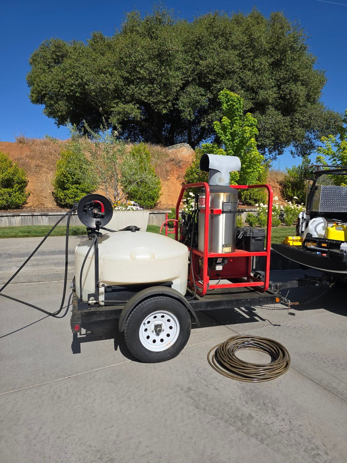 A trailer with a hose attached to it is parked next to a jeep.