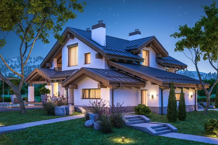 Two-story white house with wooden accents at night, illuminated by warm lights. Green lawn and trees.