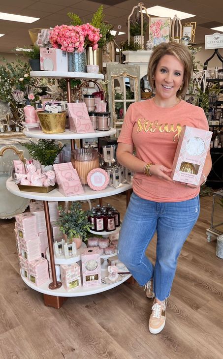 A woman is standing in front of a display in a store holding a box.