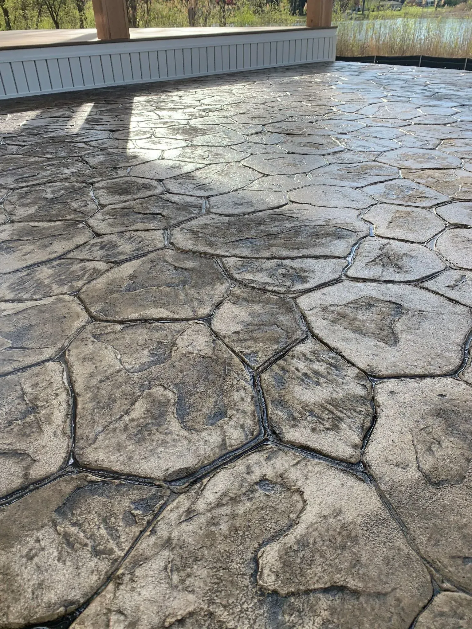 Textured, gray concrete patio with irregular stone pattern.