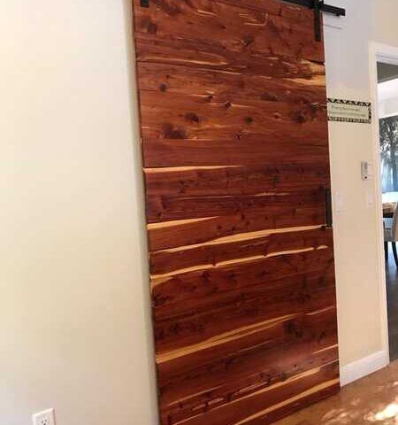 Rustic wooden sliding barn door mounted on a beige wall inside a home.