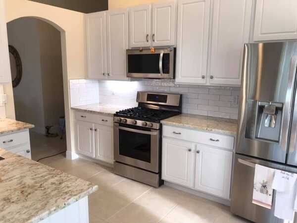 Modern kitchen with white cabinets, stainless steel appliances, and granite countertops