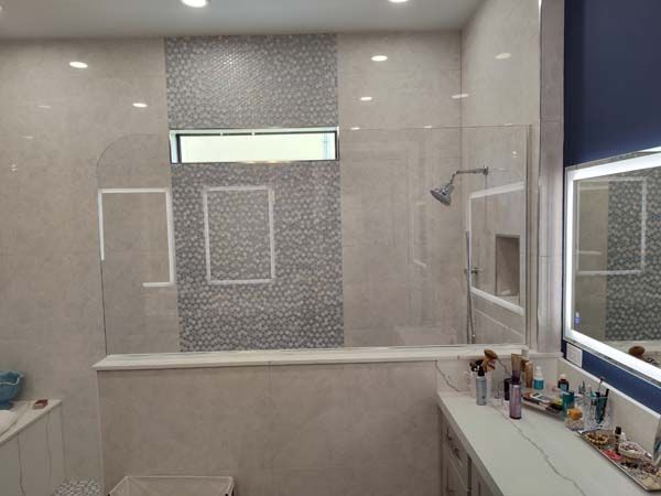 Modern bathroom with a large walk-in shower, white vanity, and illuminated mirror.