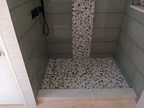 Tiled walk-in shower with mosaic floor and a built-in bench, viewed from the doorway