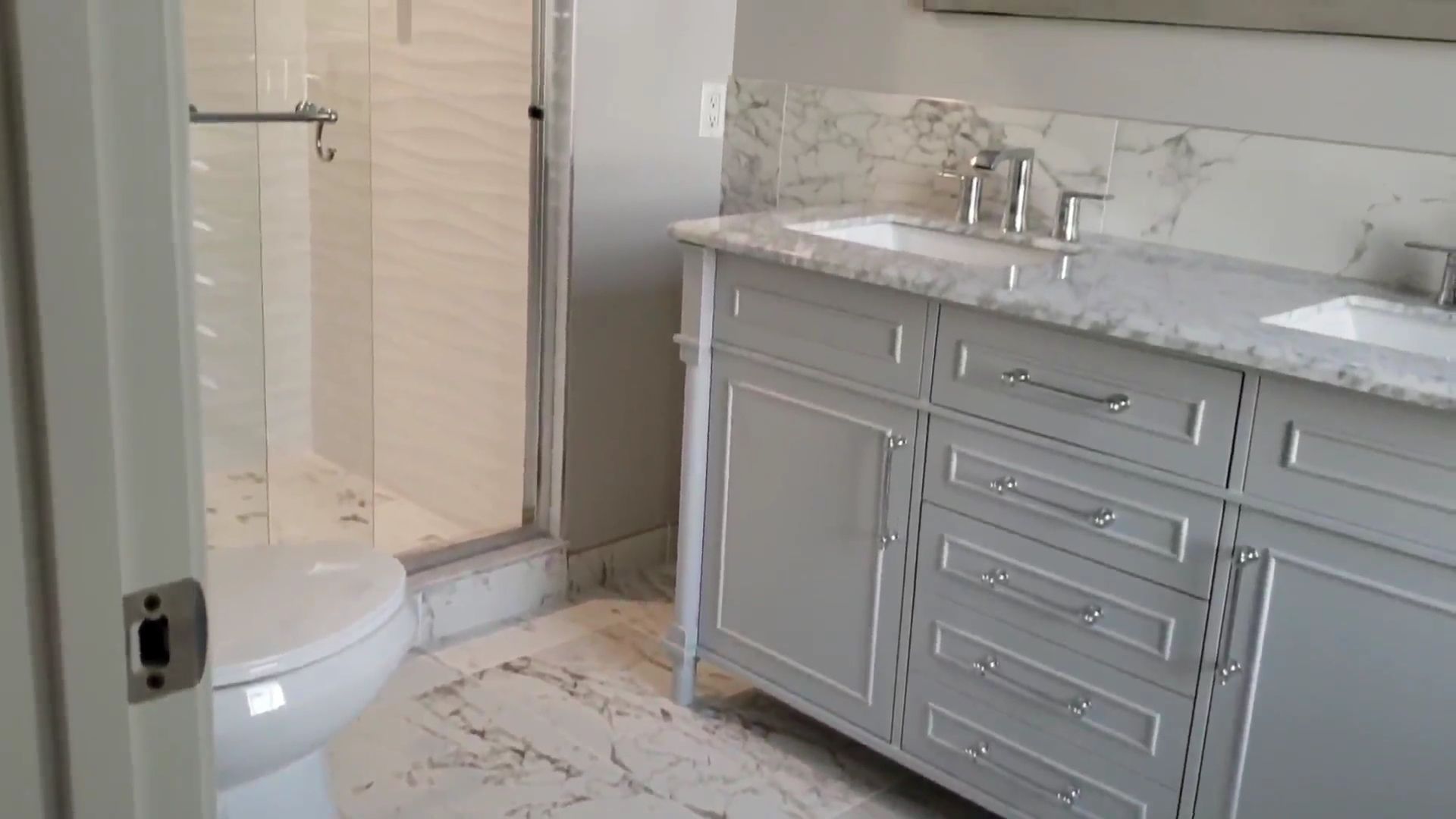 Bright modern bathroom with marble vanity, glass shower, and white toilet