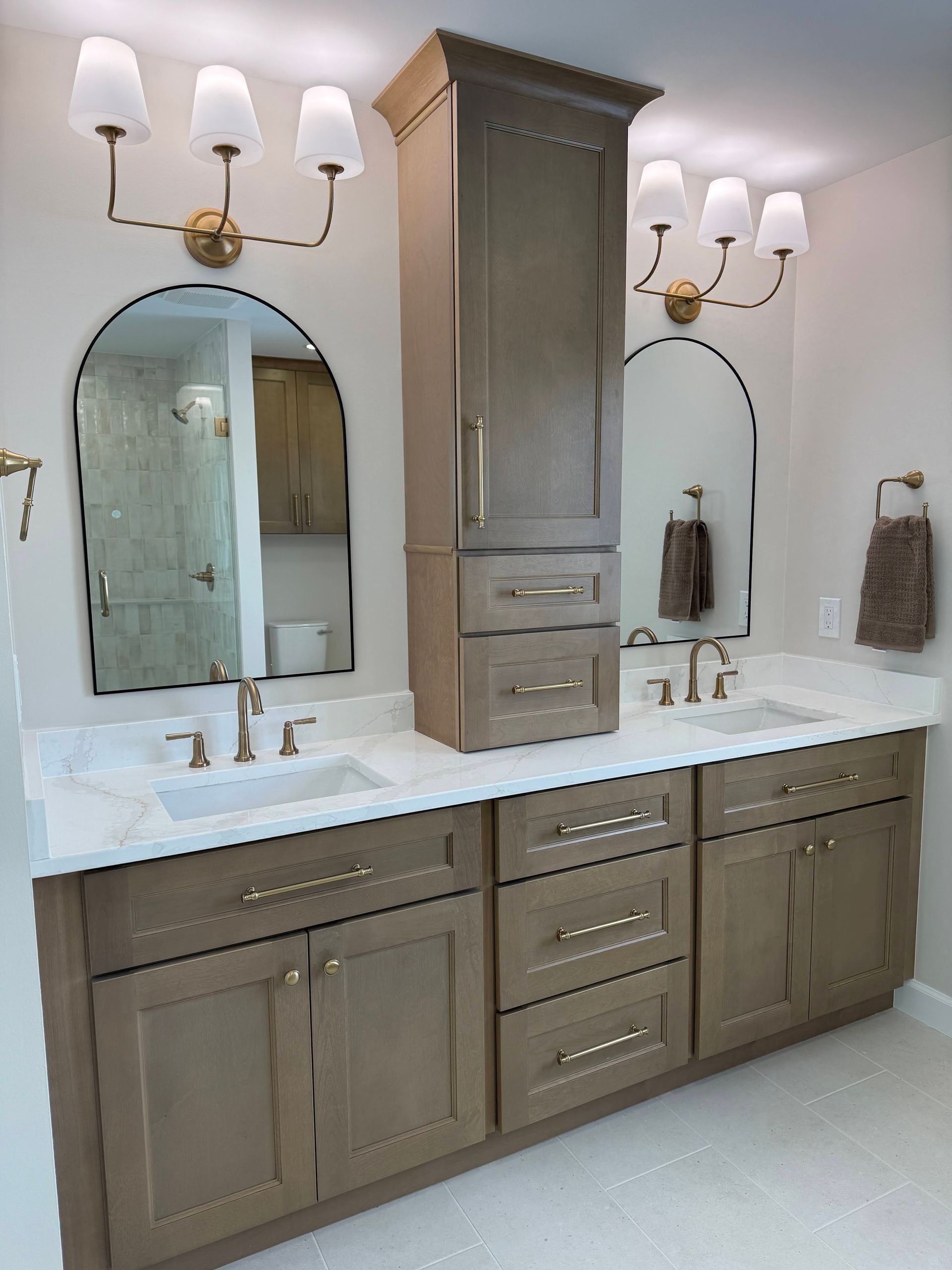 Bathroom vanity with double sinks, white countertop, mirrors, and gray cabinets under wall sconces