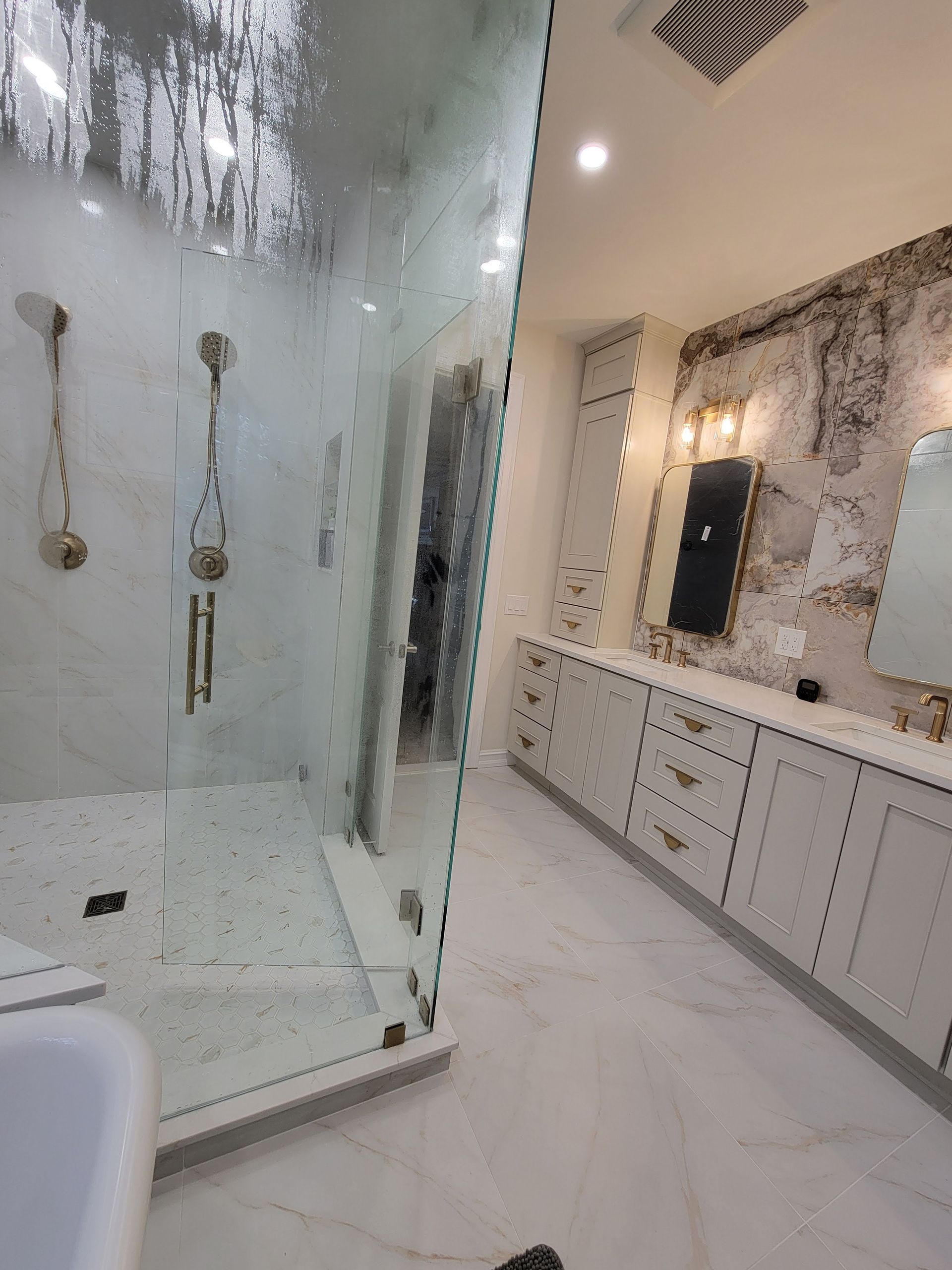 Modern bathroom with glass shower, marble floors, and vanity with mirror and drawers