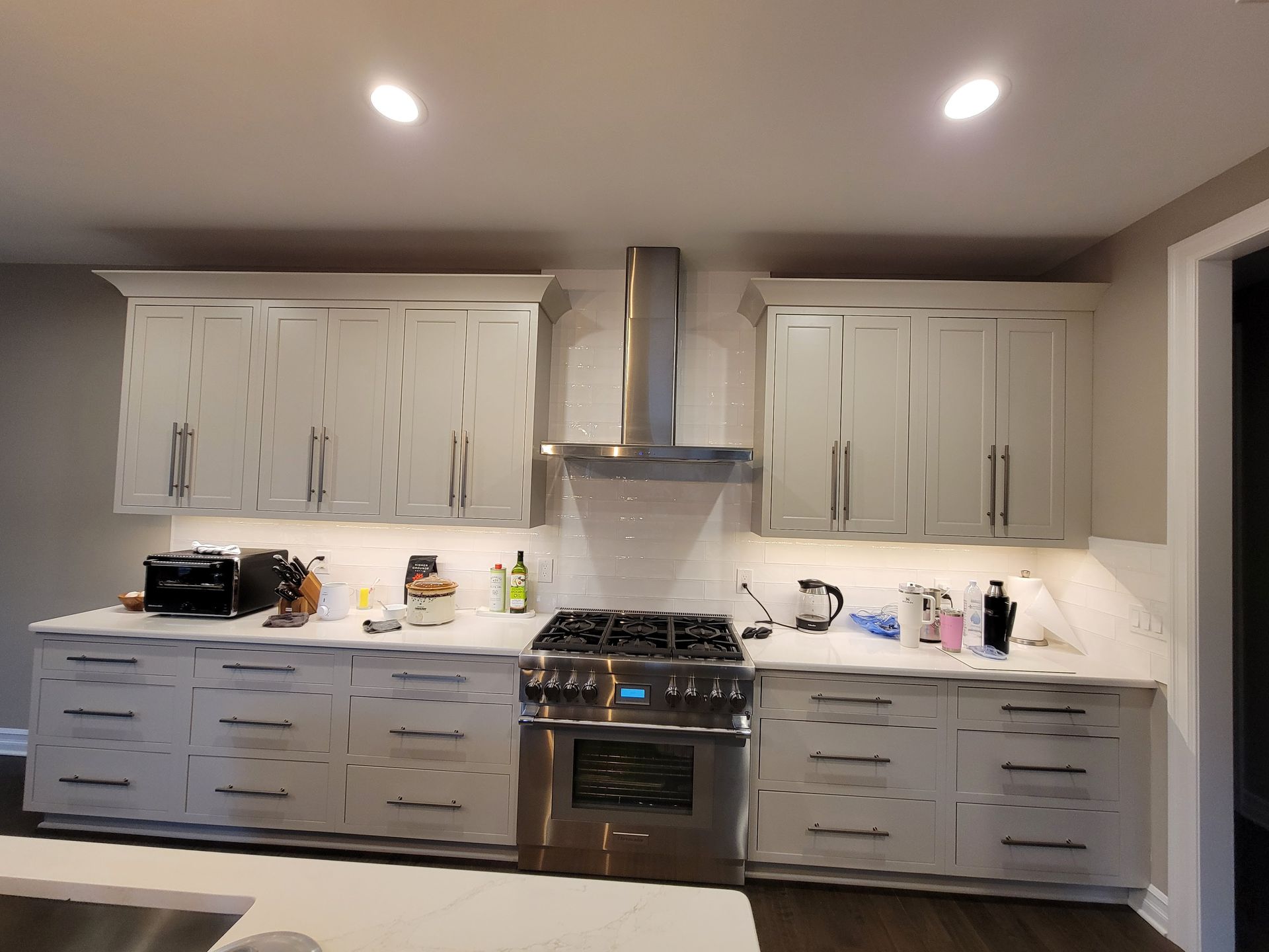 Modern kitchen with gray cabinets, marble backsplash, stainless range, and countertop items