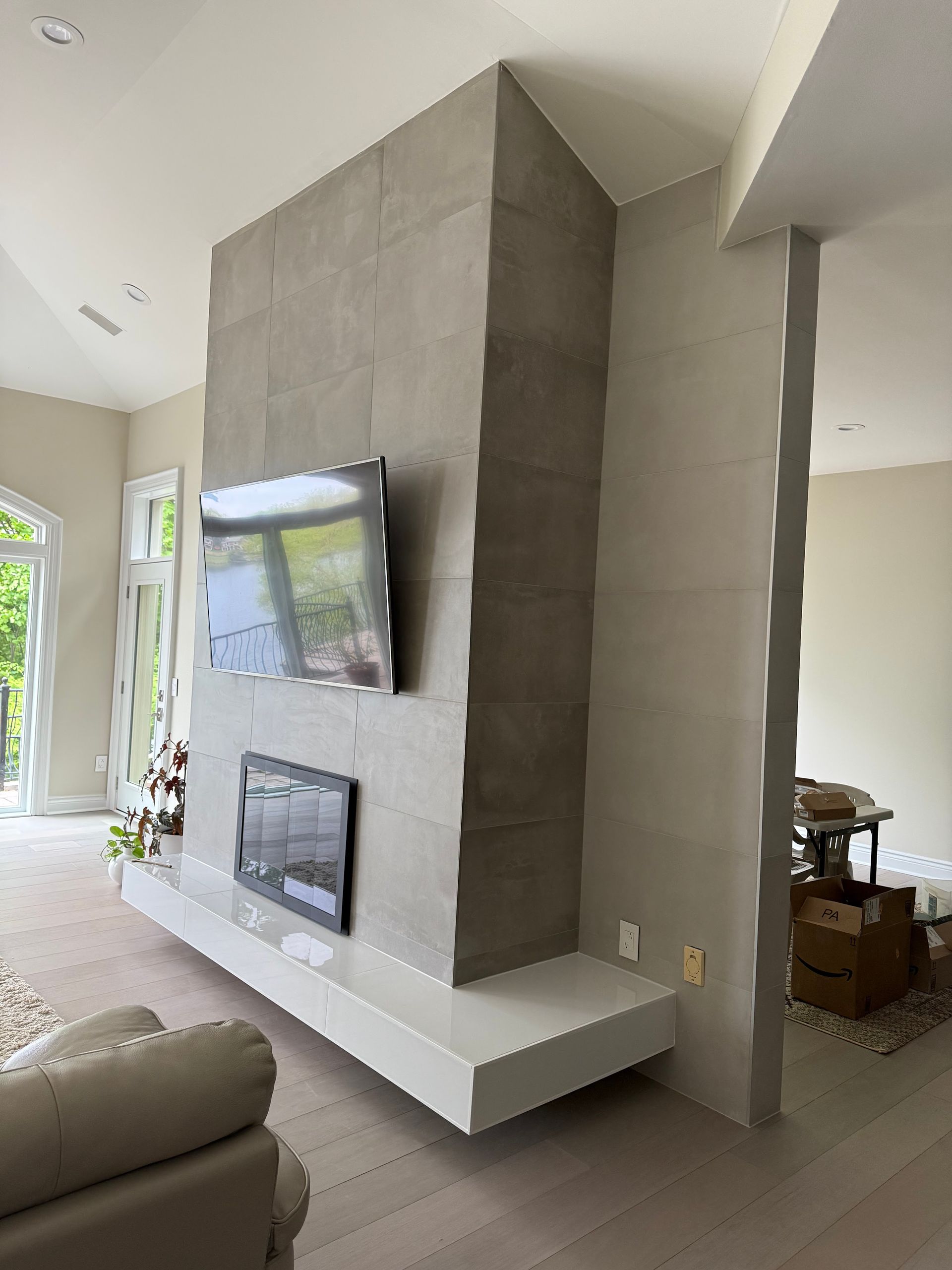 Modern living room with a gray concrete fireplace wall, mounted TV, and white built-in shelf