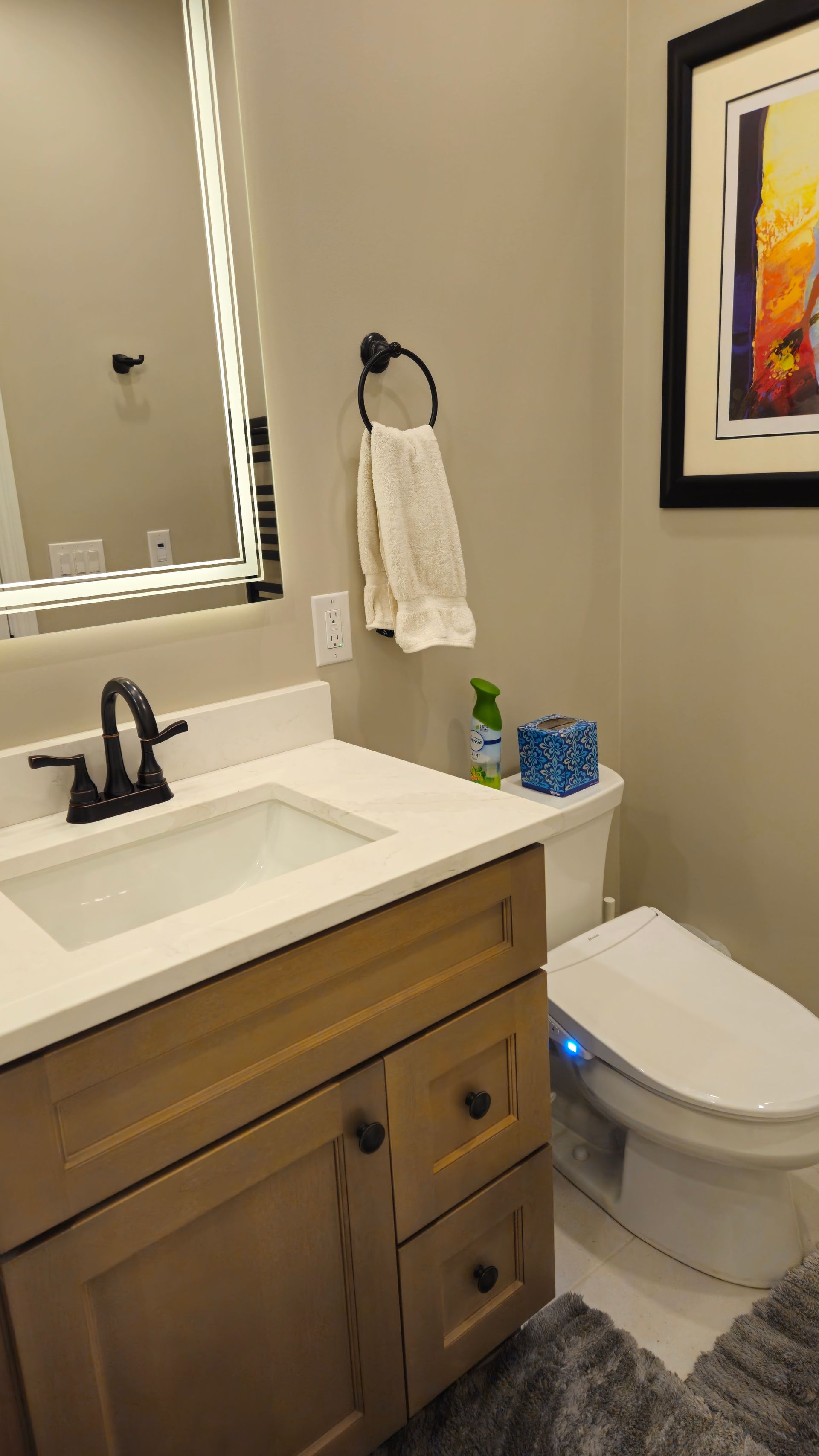 Modern bathroom with vanity, mirror, sink, toilet, and framed wall art.