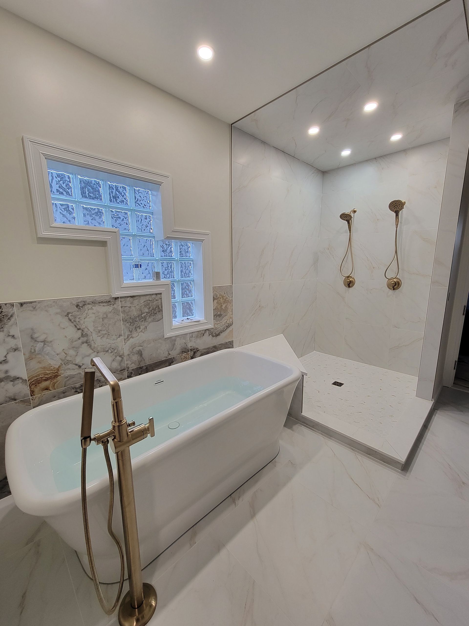 Modern white bathroom with freestanding tub, walk-in shower, and gold fixtures