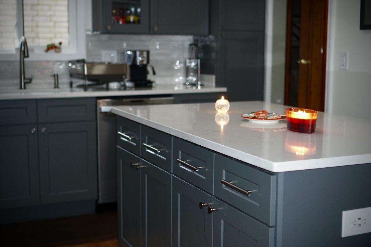Modern kitchen with gray cabinets, white island countertop, and lit candles on the counter