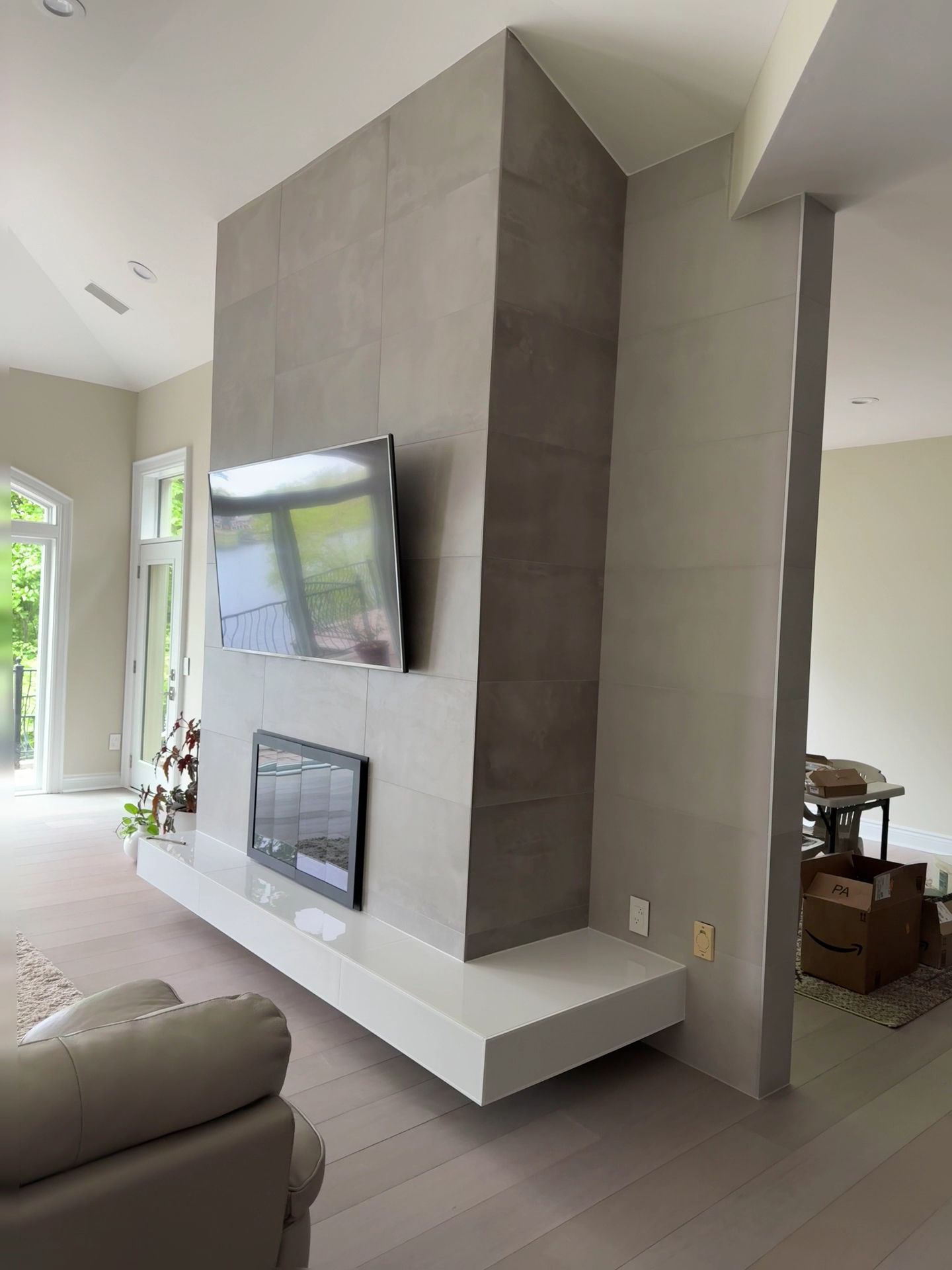Living room with a modern stone fireplace wall, mounted TV, and floating white mantel.