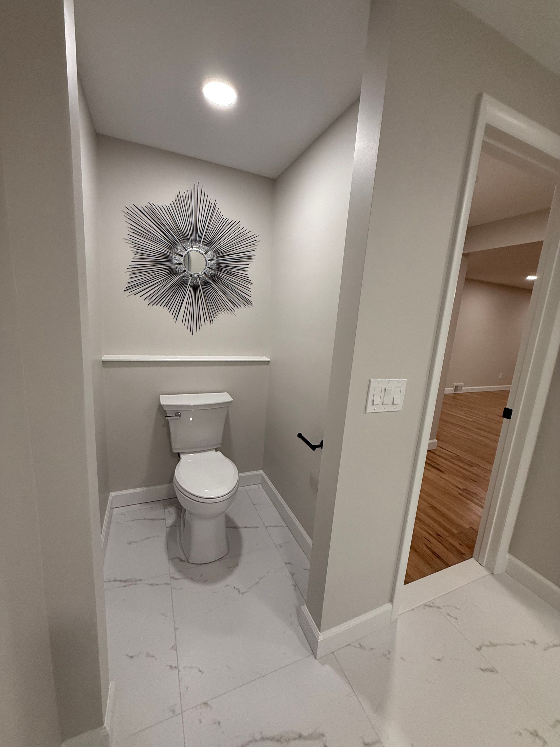 Small modern bathroom with white toilet, tiled floor, and decorative wall art