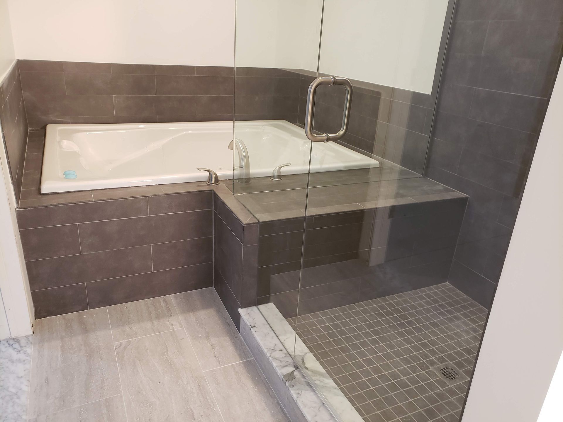 Modern bathroom with a tiled bathtub, glass shower partition, and large walk-in shower floor