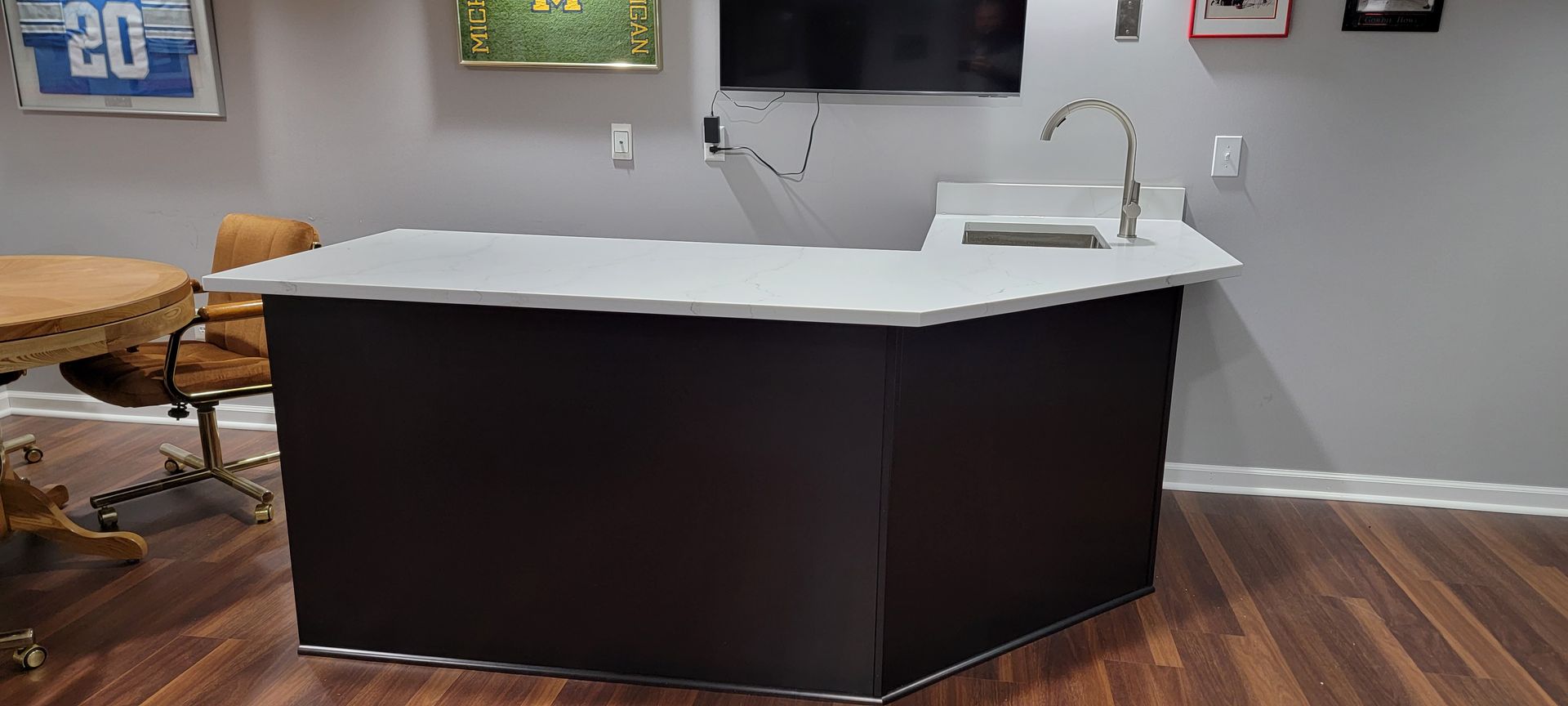 Modern kitchen island with white countertop and dark cabinets in a room with wood floors