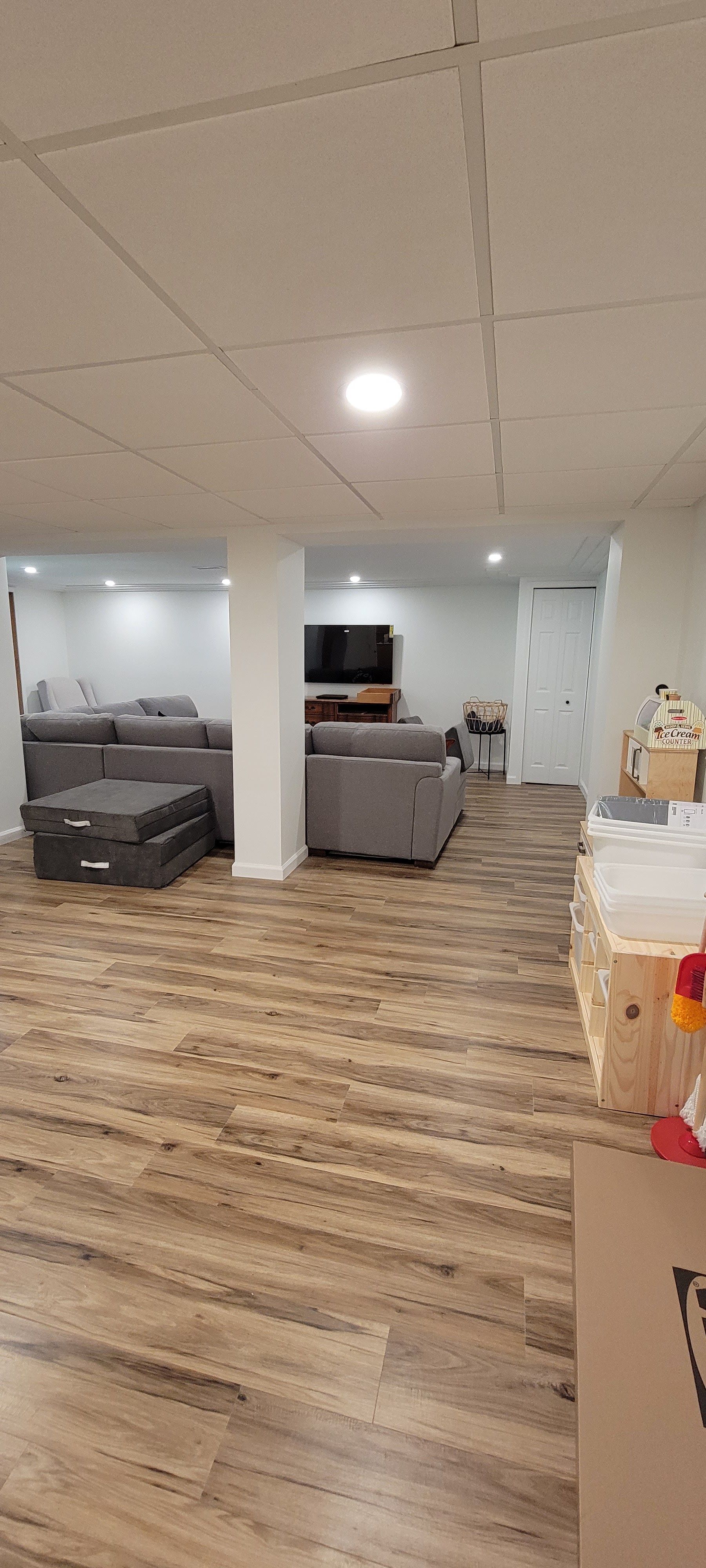 Open office lounge with gray sofas, wood floors, and a bright ceiling light
