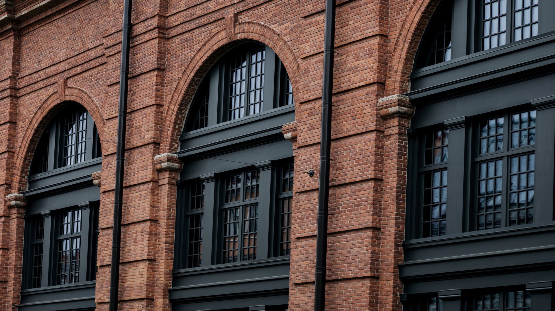 A historic red brick building facade featuring multiple large.