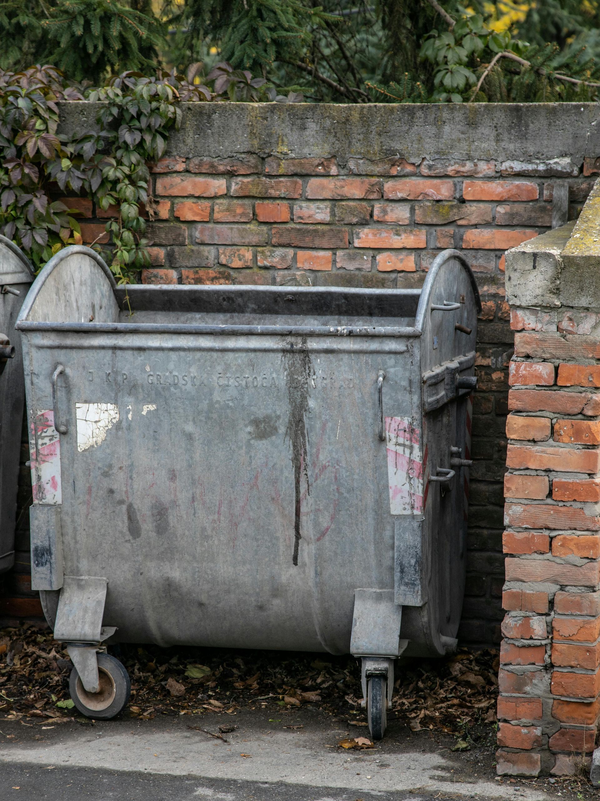 A brown, fenced trash enclosure with two sets of double doors.