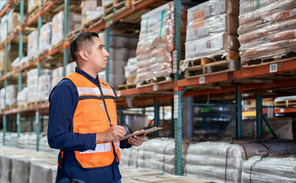 Supervisor con chaleco de seguridad naranja realizando conteo de inventario