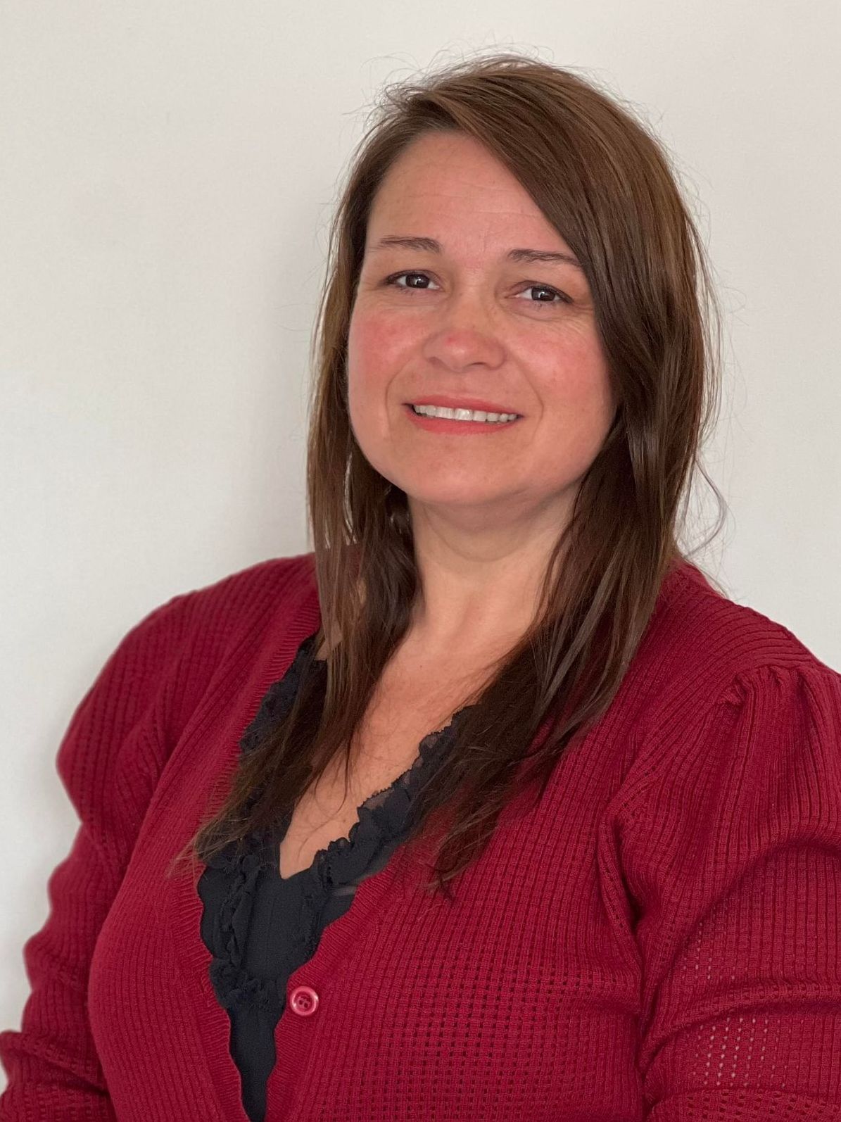 A woman in a red sweater is smiling for the camera.