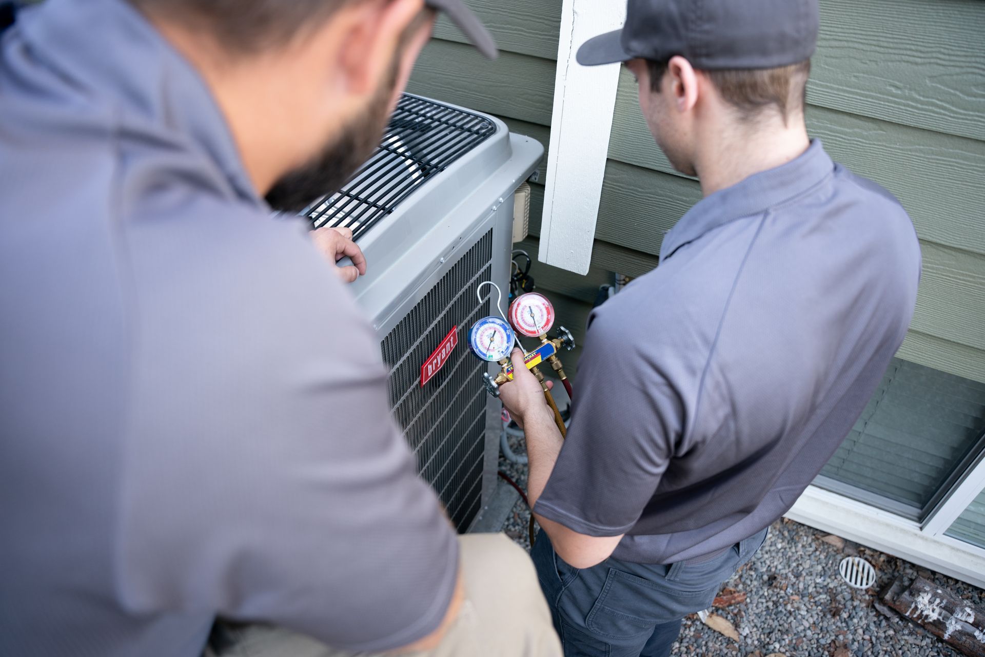 A man is working on an air conditioner outside of a house.