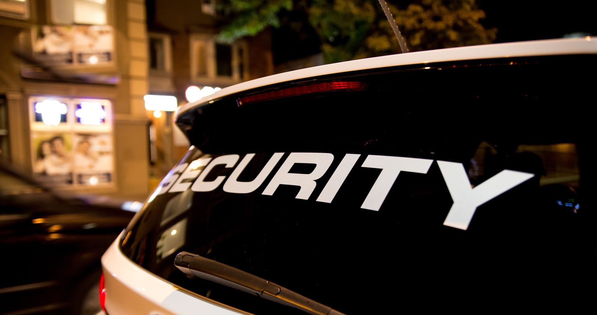 Security decal on a car window at night with city lights in the background