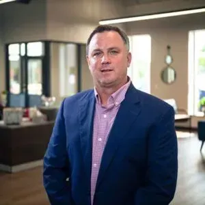 Man in a blue blazer and pink shirt standing in a modern office lobby