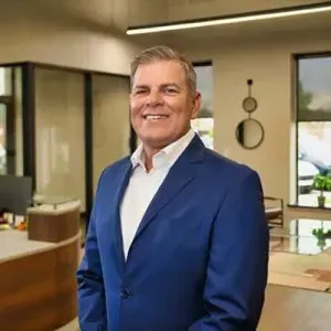 Smiling man in a blue blazer standing in a modern office lobby