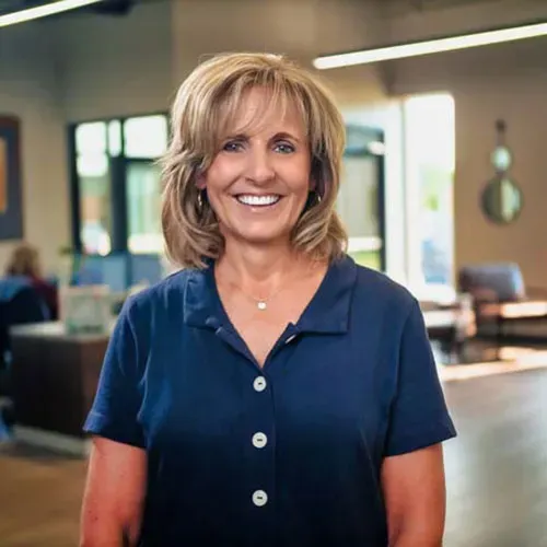 Smiling woman in a navy polo standing in a bright office