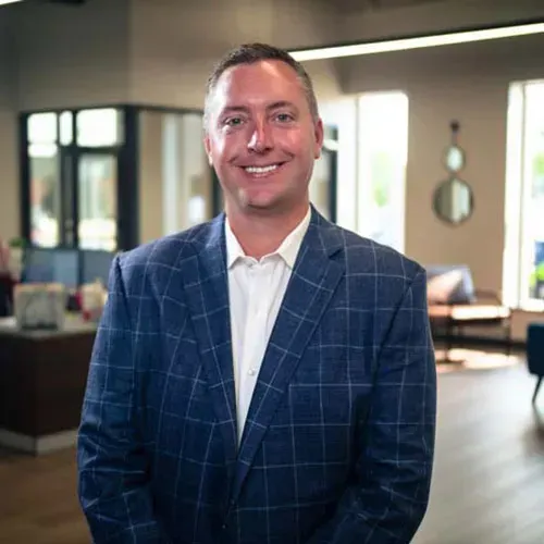 Smiling man in a blue plaid suit standing in a modern office lobby